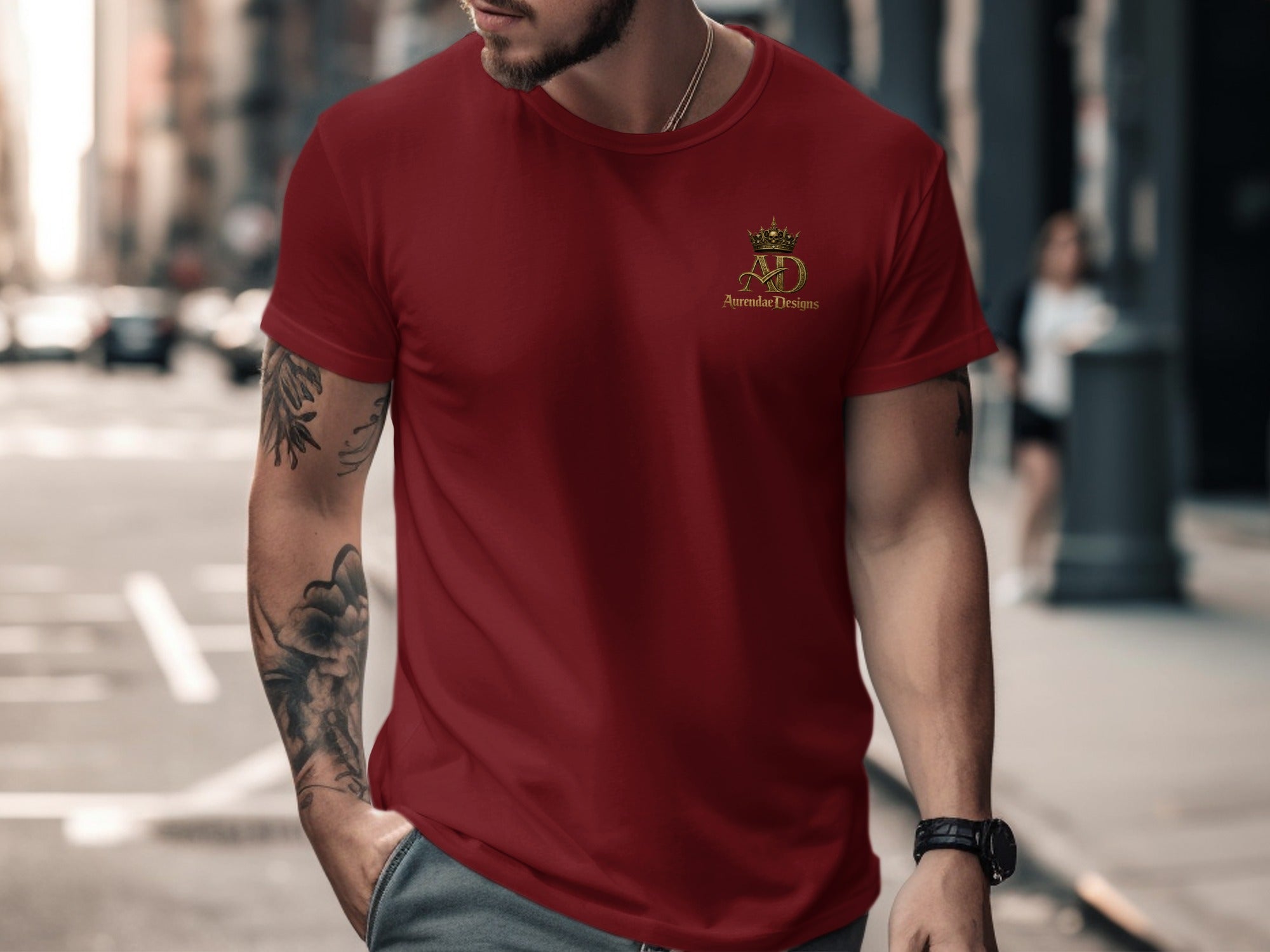 Man wearing a dark red t-shirt with a gold crown and AD logo.